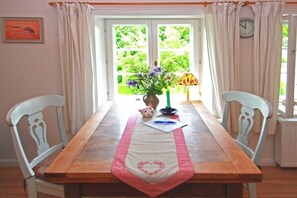 Ein Esstisch mit Blumen in einer Vase, einer Lampe und einer Uhr an der Wand.
