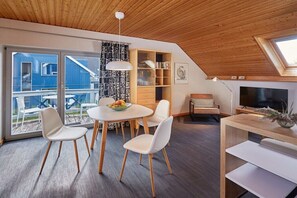 Um interior moderno com uma sala de jantar, estante de livros e televisão.