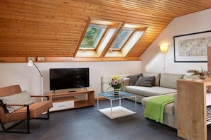 A modern living room with a television, sofa, coffee table, and skylights. - House on the dike, harbor 3a, upper floor, 47m² (Prerow)