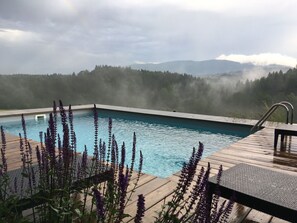 A swimming pool with a wooden deck and a view of a forested mountain range. - Holiday Home With 2 Bedrooms (Wonneberg)