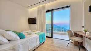 A hotel room with a bed, a desk, a chair, a TV, and a balcony with a view. - Melas Cretan Horizon (Kefalas)
