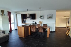 A modern kitchen with a central island, dining table, and chairs. - North Sea Resort Friesland (Schillig)
