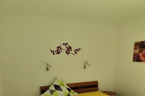 A bedroom with a bed, a wall-mounted light fixture, and a decorative floral decal. - North Sea Resort Friesland (Schillig)