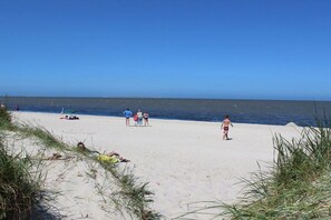 Een strand met mensen, een heldere lucht en de oceaan.