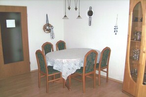A dining area with a round table, six chairs, and a white tablecloth. - Holiday apartment with 2 bedrooms (Werdum)