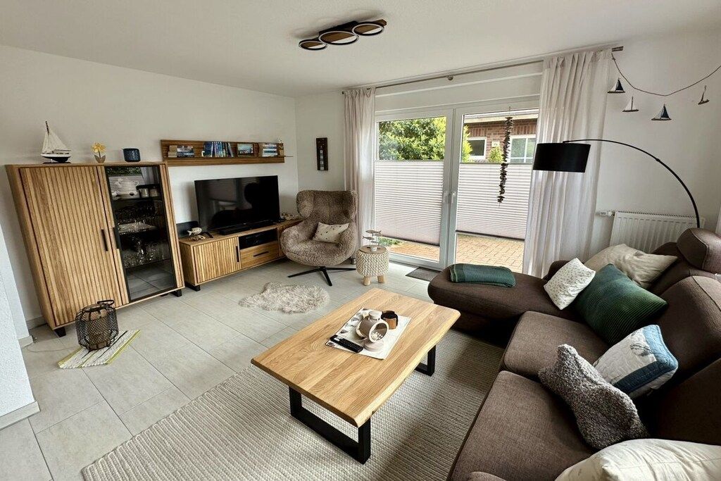 Una sala de estar con televisor, sofá, mesa de centro y puerta corrediza de vidrio que da a un área exterior.