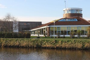 Ein Gebäude mit modernem Design, das einen markanten Turm und eine große Glasfassade aufweist.