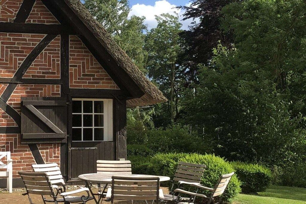 Een traditioneel bakstenen gebouw met rieten dak, een houten deur en een klein raam.