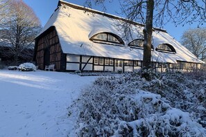 A traditional half-timbered house with a steeply pitched roof, surrounded by snow-covered ground and trees. - Karstedt Court||Lübeck - Brodten (Lübeck-Brodten Travemünde)
