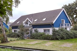 Ein zweistöckiges Haus mit geneigtem Dach, einem Balkon und einem gepflegten Garten.