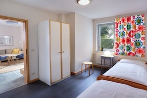 Ein Schlafzimmer mit Bett, Kleiderschrank, Schreibtisch und einem Fenster mit Vorhängen.