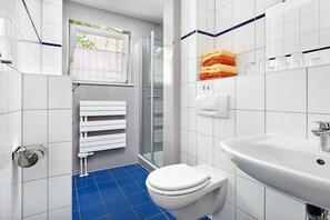 Un bagno con un water bianco, un lavandino e una cabina doccia in vetro.