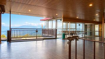 A spacious indoor area with a wooden floor and a balcony overlooking a mountainous landscape.