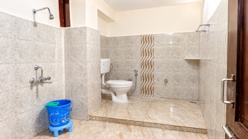 Casa de banho com sanita, chuveiro e um balde azul.
