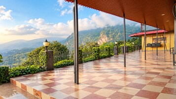 Um terraço com piso xadrez, um poste de luz e vista para uma paisagem montanhosa.