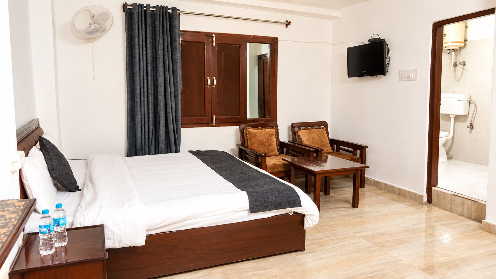 A hotel room with a bed, a desk, a chair, a television, and a bathroom.