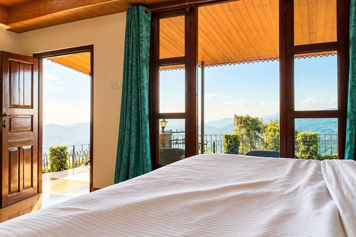 A bedroom with a large bed, wooden ceiling, and a balcony with a view of the mountains.