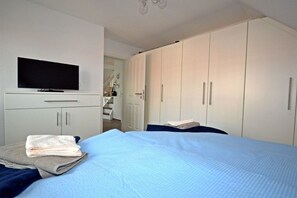 Een slaapkamer met een bed, een televisie op een meubel en een kledingkast.
