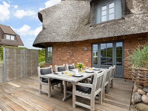 A thatched-roof house with a dining area featuring a wooden table and chairs. - Bals Seedune 9a Sturmhues (Wenningstedt-Braderup)
