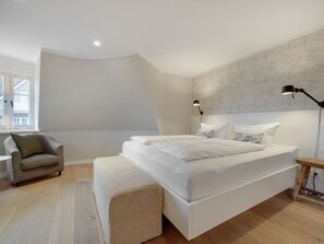 A bedroom with a large bed, a chair, a bedside table, and a lamp. - Bals Seedune 9a Sturmhues (Wenningstedt-Braderup)