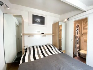 A modern bedroom with a bed, a mirror, a picture, and a bathroom visible through an open door. - Do04 Holiday Home Domburg (Domburg)