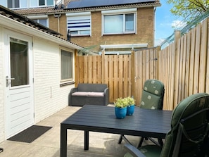 A patio with a table and chairs, a wooden fence, and a building in the background. - Do04 Holiday Home Domburg (Domburg)