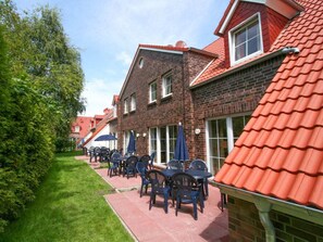 A courtyard with outdoor seating, brick buildings, and a red-tiled roof. - Holiday Home With 3 Bedrooms (Krummhoern)