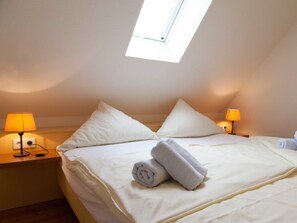 A hotel room with a bed, two bedside lamps, a window, and a rolled towel on the bed. - Holiday Home With 3 Bedrooms (Krummhoern)
