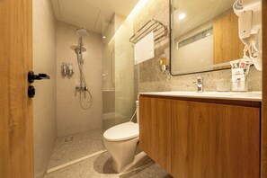 Een moderne badkamer met een glazen douchecabine, toilet en een wastafel met spiegel.