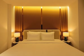 Een hotelkamer met een bed, twee bedlampen en een hoofdeinde met verticale lichtstroken.