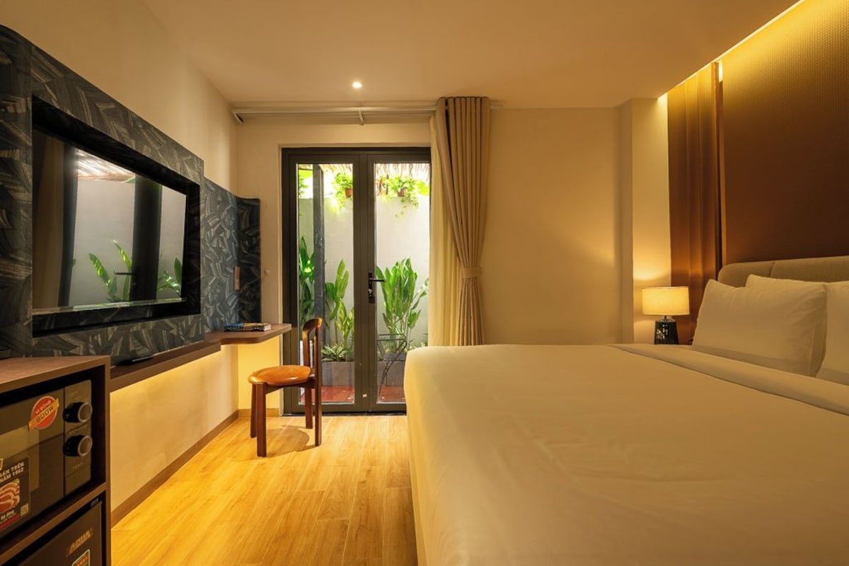 Een hotelkamer met een bed, een televisie, een bureau en een stoel.