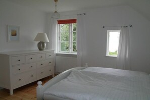 Ein Schlafzimmer mit einem Bett, einem Schminktisch, einem Fenster mit Vorhängen und einer Lampe.