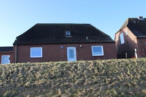 A two-story brick house with a sloped roof, a front door, and two windows on the ground floor. - Holiday home with 1 bedroom (Nordstrand)