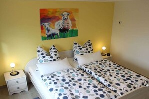 A bedroom with a bed, two bedside tables, and a painting on the wall. - Holiday home with 1 bedroom (Nordstrand)