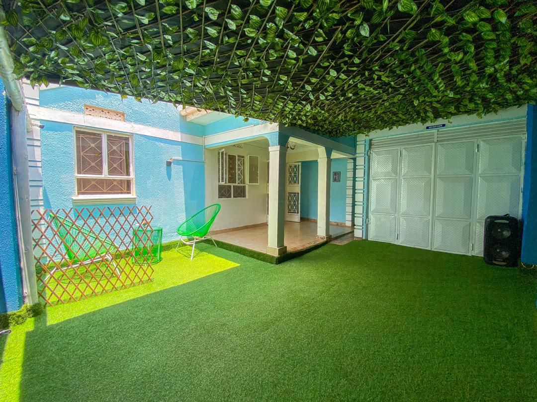 Un espacio al aire libre cubierto con césped artificial, una silla verde y una puerta de garaje blanca.