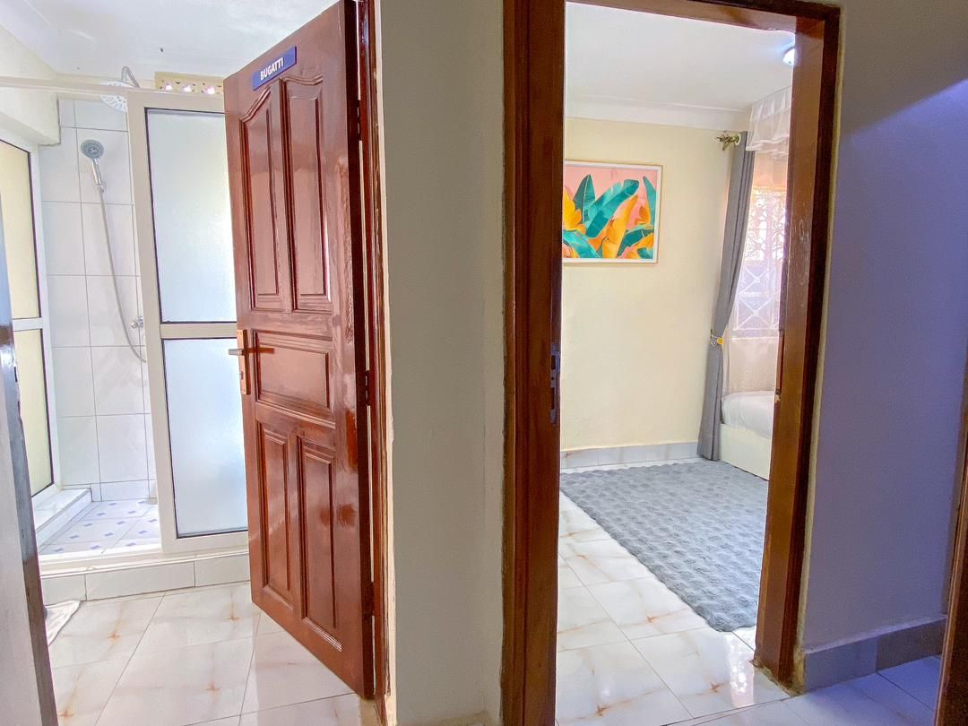 A room with a wooden door, a shower area, and a colorful abstract painting on the wall.