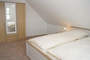 A bedroom with a bed, a wardrobe, and a mirror. - Terraced house with 2 bedrooms (Sylt Ost\/ Tinnum)
