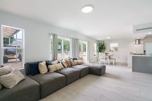Una sala de estar moderna con un sofá modular, un comedor y una cocina.