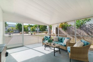 A covered outdoor seating area with wicker furniture and a view of the neighborhood. - Relaxation Time: Fenced yard, Screened Porch, Close to the Beach (Key Largo)