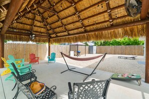 Un espacio al aire libre cubierto con una hamaca, sillas y una mesa.
