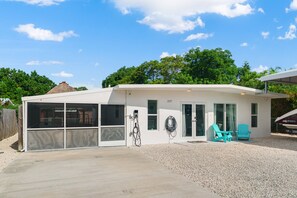 A modern house with a covered patio, a garage, and a boat docked outside. - Relaxation Time: Fenced yard, Screened Porch, Close to the Beach (Key Largo)