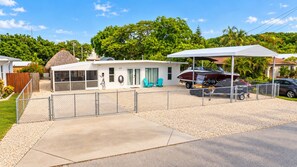 Propiedad residencial con un espacio exterior techado, una parrilla y un vehículo.