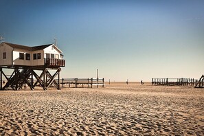 A lifeguard tower on a sandy beach with a wooden walkway leading to it. - Margarethenhof - No. 2 (Tetenbüll)