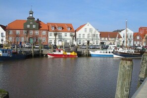 Ein Hafen mit vertäuten Booten, Gebäuden mit roten Dächern und einem klaren Himmel.