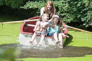 A boat with three people on a body of water surrounded by greenery. - Margarethenhof - No. 2 (Tetenbüll)