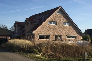 Ein Haus aus Backsteinen mit einem geneigten Dach und mehreren Fenstern.