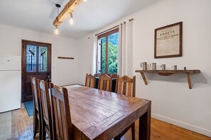 Ein Esszimmer mit Holztisch und -stühlen, einem fenster mit Vorhängen, einem befestigten Schild und einer Holzablage mit Gegenständen.