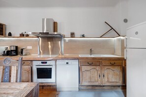 Eine moderne Küche mit Edelstahlgeräten, Holzschränken und einem eingebauten Ofen.