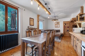 A rustic kitchen with wooden furniture, a dining table, and a built-in bookshelf. - Apartment 'Appartement de montagne' (Queige)