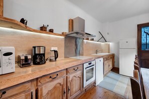 A modern kitchen with wooden cabinetry, a stainless steel range hood, a coffee maker, and a dishwasher. - Apartment 'Appartement de montagne' (Queige)